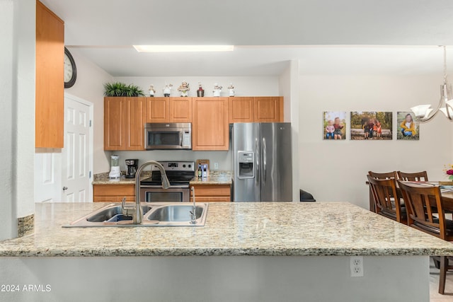 kitchen featuring kitchen peninsula, light stone countertops, sink, and appliances with stainless steel finishes