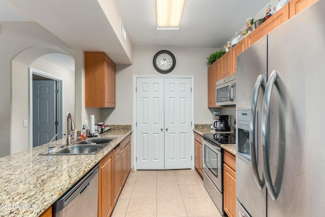 kitchen featuring light stone counters, sink, light tile patterned floors, and appliances with stainless steel finishes