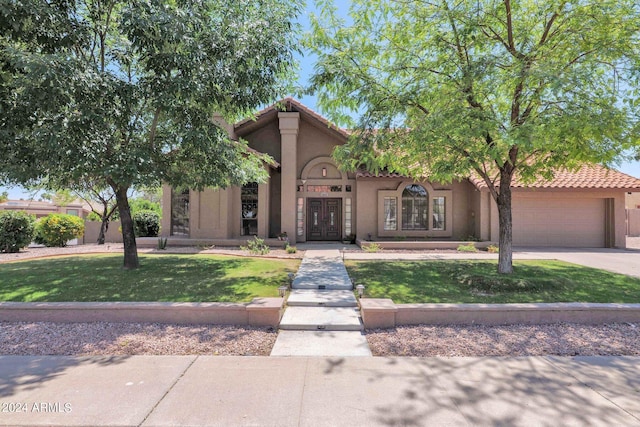 mediterranean / spanish house featuring a front lawn, a tiled roof, concrete driveway, stucco siding, and a garage