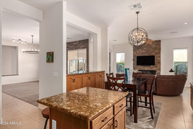 kitchen featuring decorative light fixtures, a fireplace, a chandelier, and light carpet