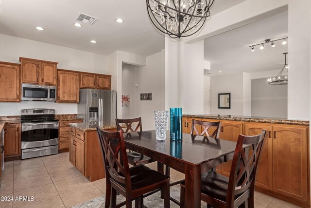 kitchen featuring stone countertops, a chandelier, light tile patterned floors, hanging light fixtures, and appliances with stainless steel finishes