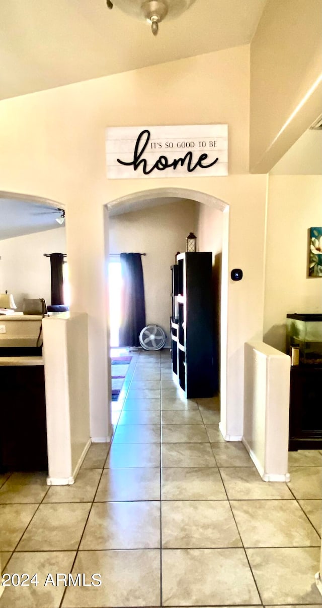 hallway with tile patterned floors and vaulted ceiling