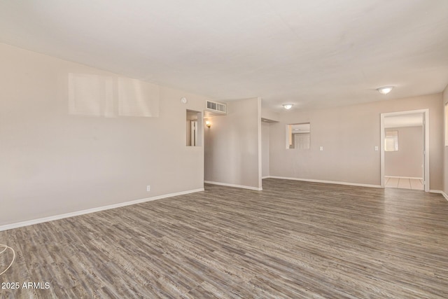 spare room with visible vents, baseboards, and wood finished floors