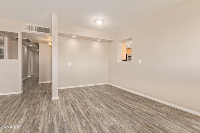 empty room with baseboards, visible vents, and wood finished floors