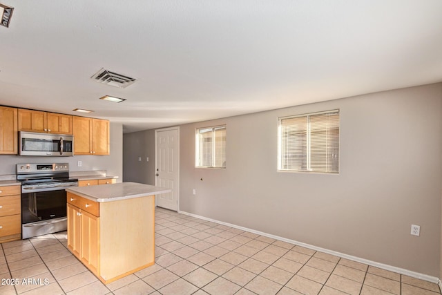 kitchen with visible vents, a kitchen island, appliances with stainless steel finishes, light countertops, and light tile patterned flooring