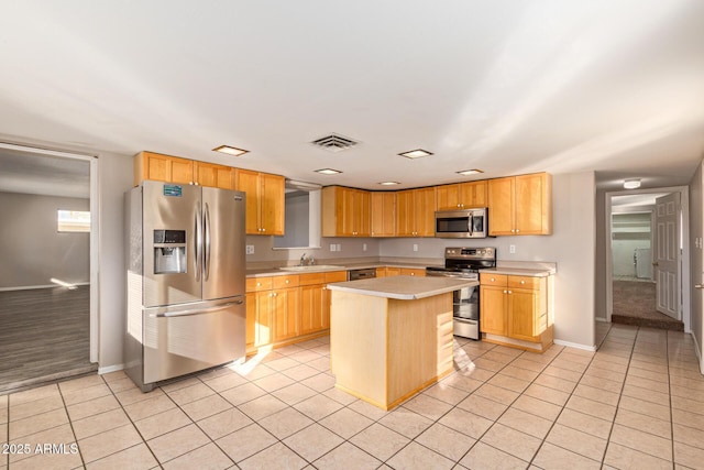 kitchen featuring appliances with stainless steel finishes, light countertops, a sink, and light tile patterned flooring