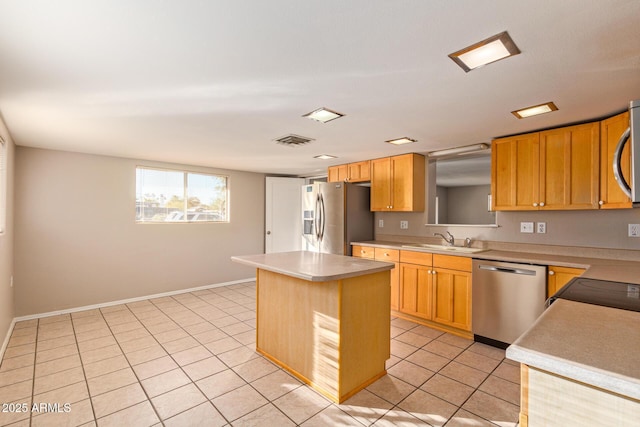 kitchen featuring visible vents, appliances with stainless steel finishes, a center island, light countertops, and a sink