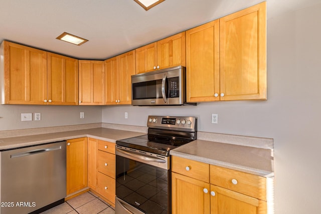 kitchen with light tile patterned floors, stainless steel appliances, and light countertops