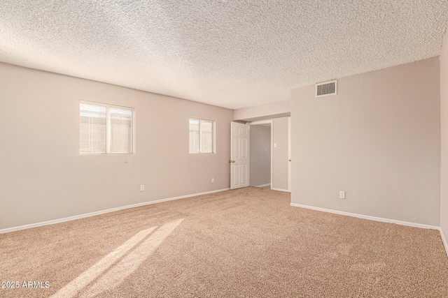 empty room with light carpet, baseboards, visible vents, and a textured ceiling