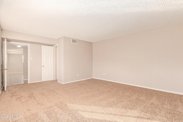 spare room with baseboards, a textured ceiling, visible vents, and carpet flooring