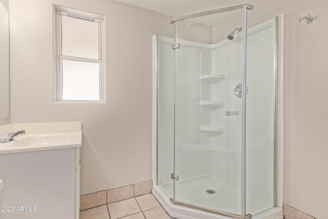 full bathroom featuring a stall shower, tile patterned flooring, baseboards, and vanity