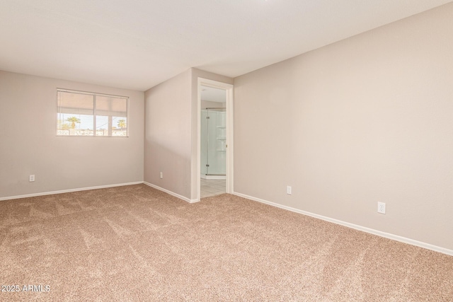 empty room featuring light carpet and baseboards