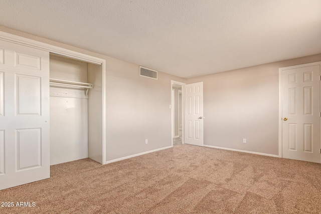 unfurnished bedroom featuring a textured ceiling, carpet floors, a closet, and visible vents