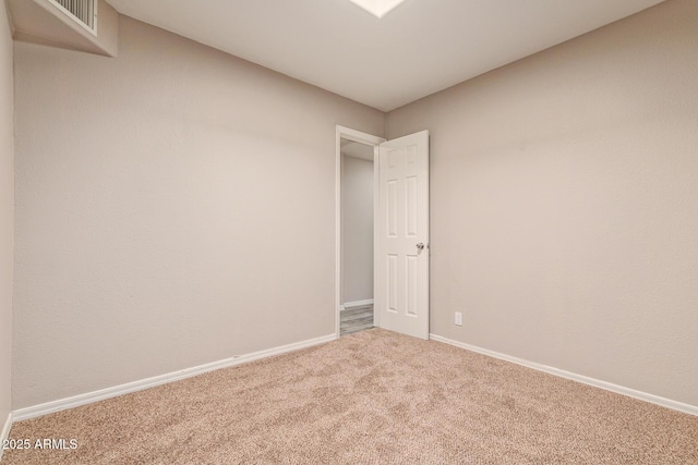 spare room with carpet, visible vents, and baseboards