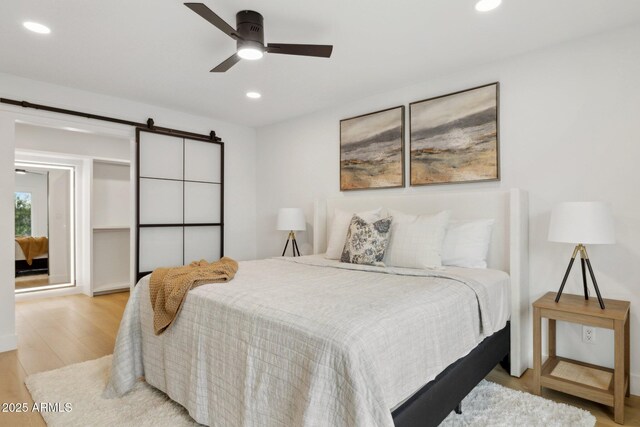 8403 E Fairmount Ave, Scottsdale, AZ 85251 - bedroom with light wood-style flooring, recessed lighting, a barn door, and ceiling fan