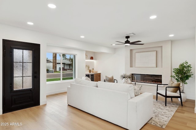8403 E Fairmount Ave, Scottsdale, AZ 85251 - living area featuring light wood-type flooring, recessed lighting, ceiling fan, beverage cooler, and a glass covered fireplace