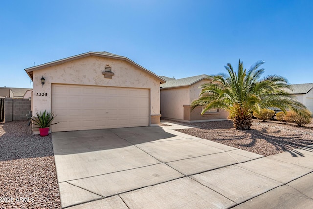 view of front facade with a garage, concrete driveway, fence, and stucco siding