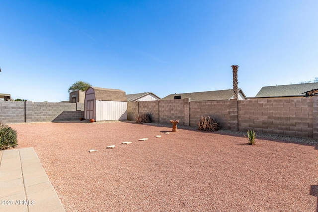 view of yard with a fenced backyard, an outdoor structure, and a storage unit