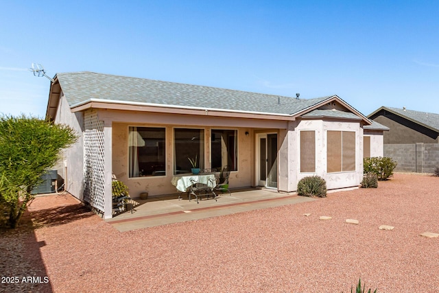 rear view of property featuring roof with shingles, stucco siding, a patio area, fence, and central AC