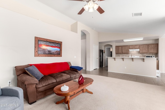 living room featuring light tile patterned floors, visible vents, arched walkways, light colored carpet, and lofted ceiling