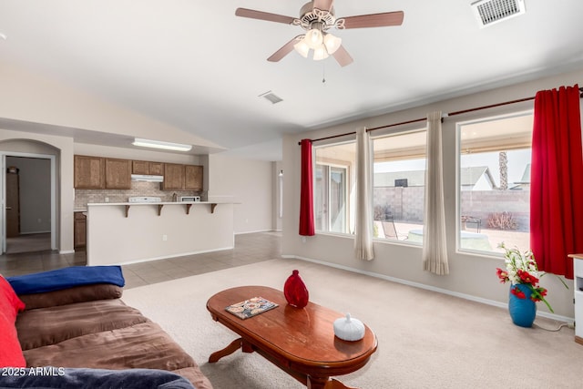 living area with light colored carpet, visible vents, and vaulted ceiling