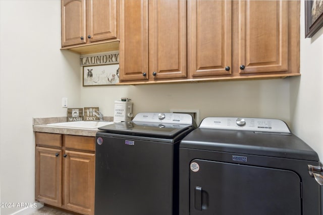 washroom with cabinets, washer and clothes dryer, and sink