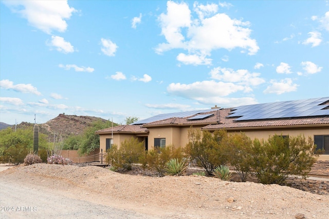 view of side of home featuring a mountain view and solar panels