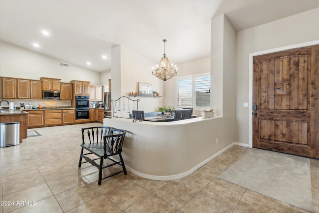 kitchen featuring appliances with stainless steel finishes, lofted ceiling, a chandelier, and light tile patterned flooring