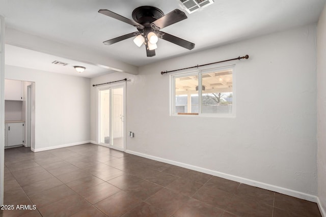 spare room with dark tile patterned floors and ceiling fan