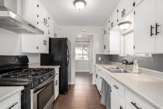 kitchen with white cabinets, dark tile patterned floors, stainless steel gas range, and wall chimney exhaust hood