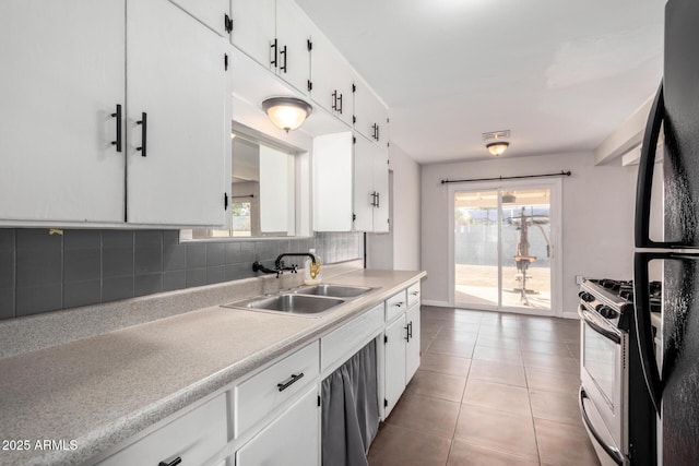 kitchen featuring white cabinetry, sink, decorative backsplash, light tile patterned floors, and stainless steel gas range