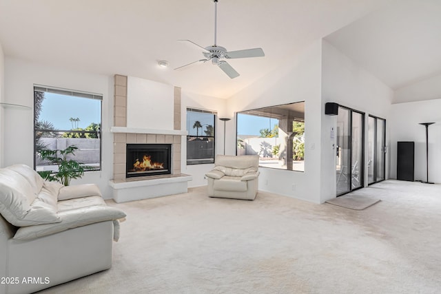 living room with vaulted ceiling, ceiling fan, carpet, and a tile fireplace