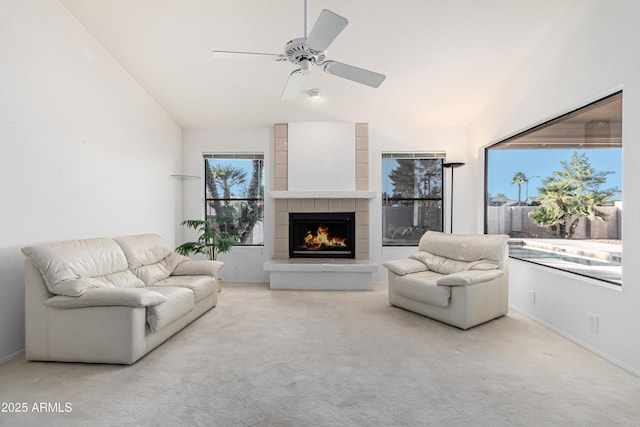 living room featuring ceiling fan, light colored carpet, a tiled fireplace, and vaulted ceiling