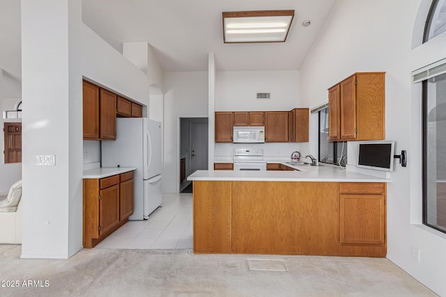 kitchen with white appliances, a towering ceiling, sink, kitchen peninsula, and light tile patterned floors