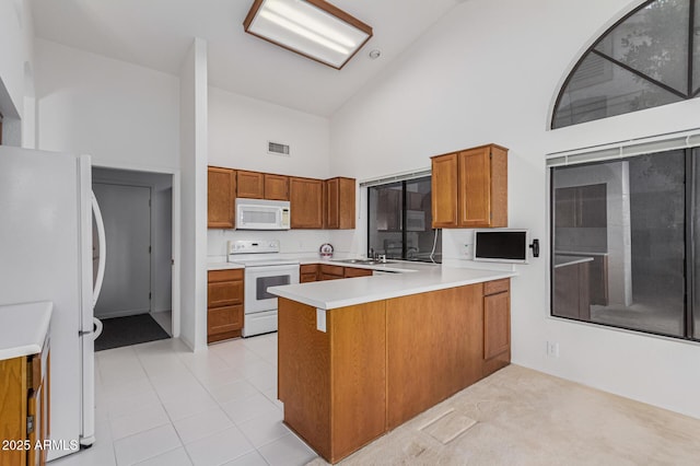 kitchen featuring white appliances, sink, kitchen peninsula, high vaulted ceiling, and light tile patterned floors