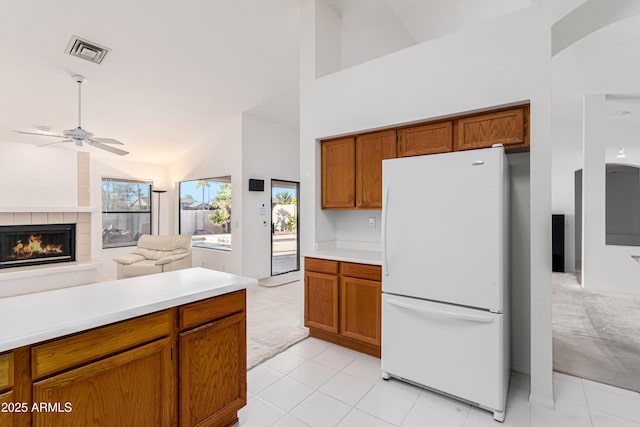 kitchen featuring ceiling fan, a tile fireplace, light carpet, high vaulted ceiling, and white refrigerator