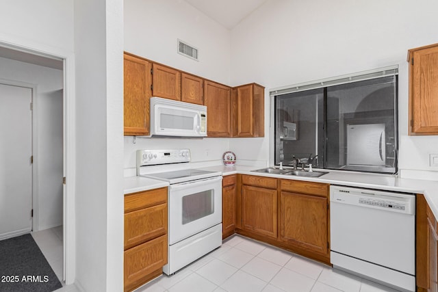 kitchen with light tile patterned floors, a towering ceiling, sink, and white appliances