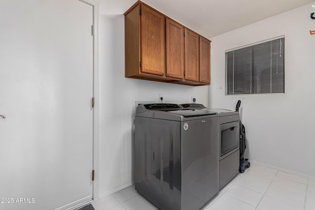 laundry area with cabinets, light tile patterned floors, and washing machine and dryer