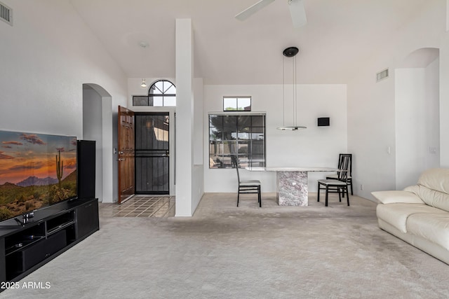 carpeted living room with ceiling fan and a towering ceiling