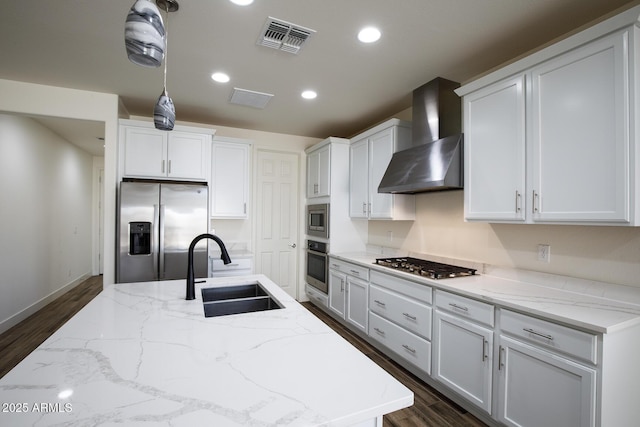 kitchen featuring visible vents, a sink, dark wood-type flooring, appliances with stainless steel finishes, and wall chimney range hood