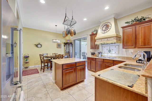 kitchen with custom exhaust hood, appliances with stainless steel finishes, sink, a kitchen island, and pendant lighting