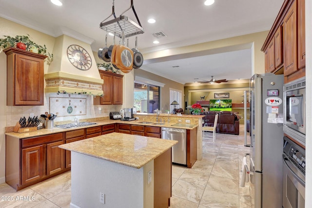 kitchen featuring sink, a kitchen island, crown molding, and appliances with stainless steel finishes