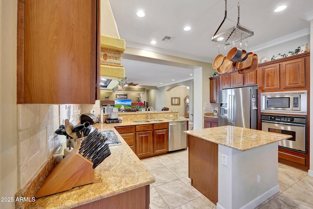 kitchen featuring light stone countertops, backsplash, kitchen peninsula, and appliances with stainless steel finishes