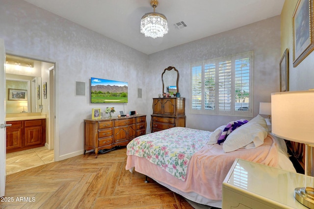 bedroom featuring light parquet floors, ensuite bath, and an inviting chandelier