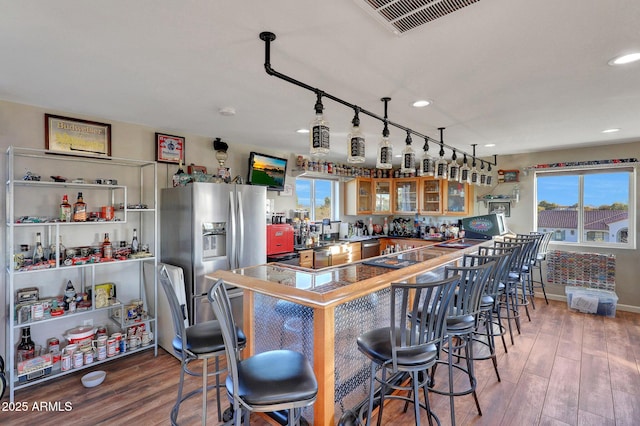 bar with hardwood / wood-style flooring, plenty of natural light, and stainless steel fridge