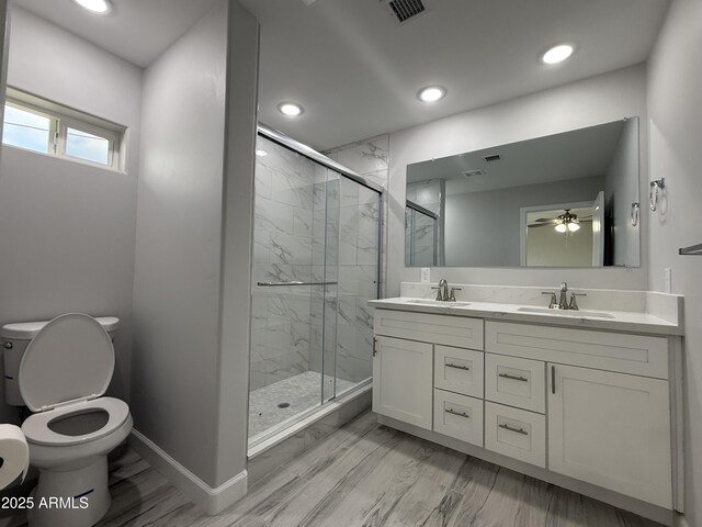 bathroom with ceiling fan, vanity, wood-type flooring, toilet, and walk in shower