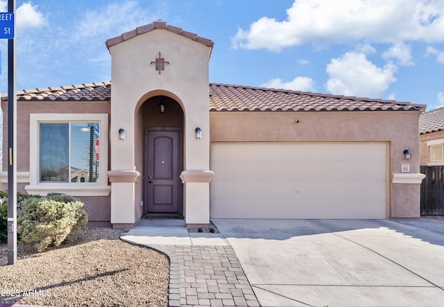 mediterranean / spanish-style home featuring stucco siding, a garage, concrete driveway, and a tiled roof