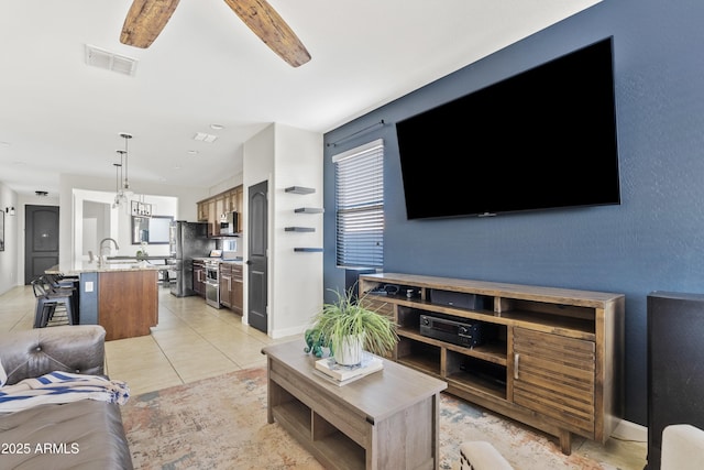 living area with light tile patterned floors, baseboards, visible vents, and ceiling fan