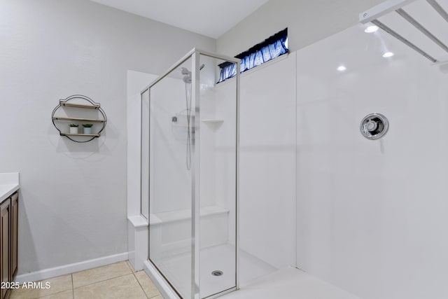 full bath featuring tile patterned flooring, vanity, baseboards, and a stall shower