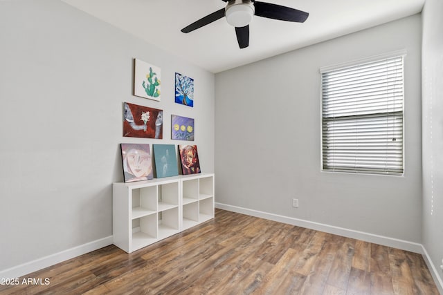 interior space with a ceiling fan, baseboards, and wood finished floors